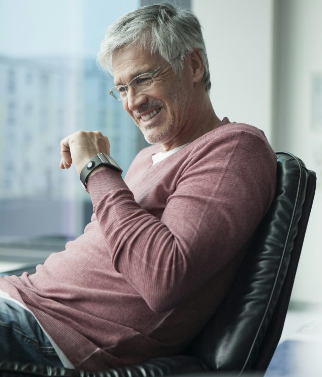 Smiling man with smartwatch sitting in a leather chair